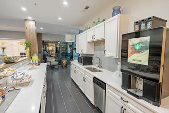 A modern kitchen with a large island and a flat screen tv mounted above the sink.